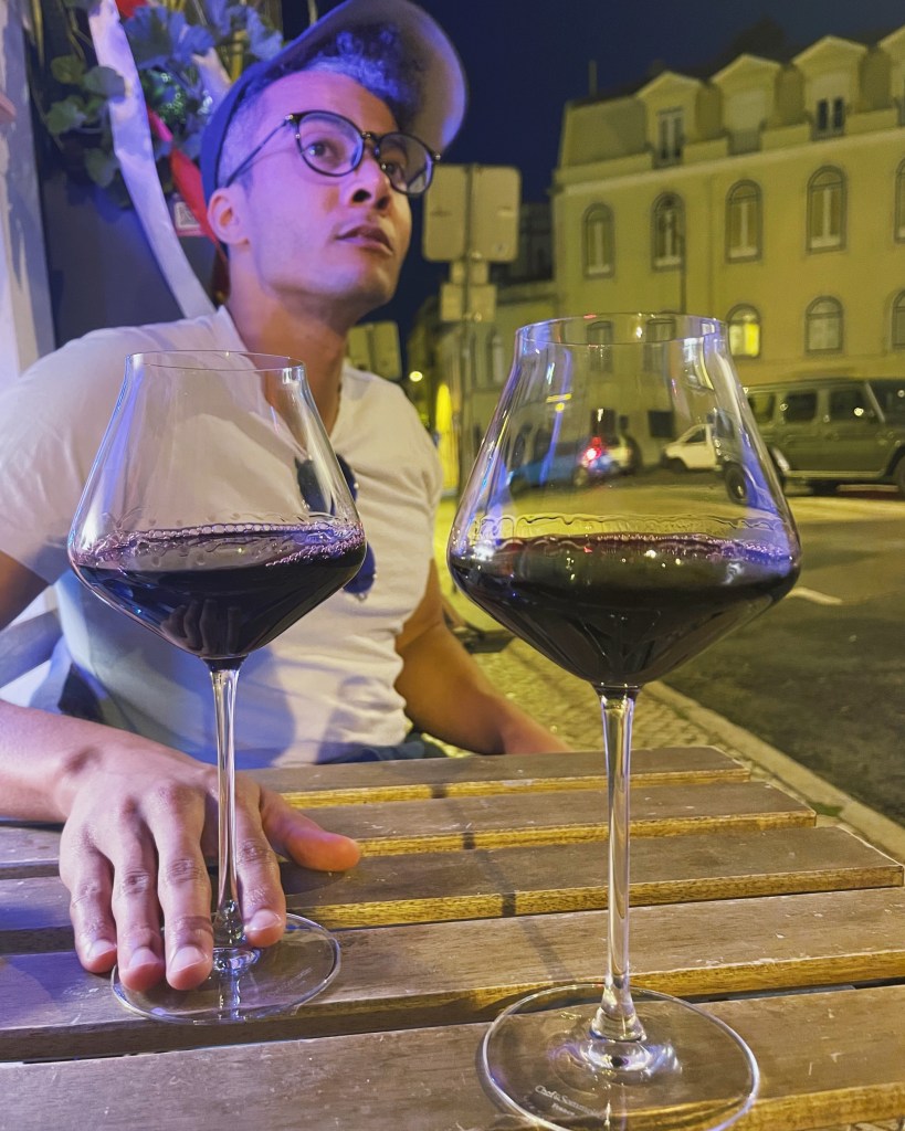 Man sitting on the sidewalk with two glasses of Georgian red wine from IF IF IF in Lisbon, Portugal